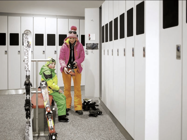 Skiiers putting skis on by lockers
